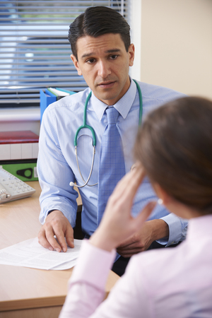 Serious Doctor In Office Giving Bad News To Female Patientの写真素材