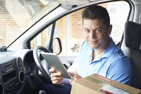 Portrait Of Courier In Van With Digital Tablet Delivering Package To Houseの写真素材