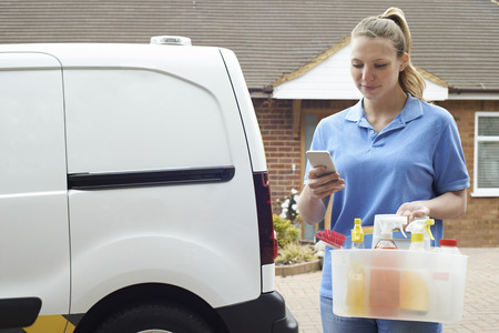 Woman Running Mobile Cleaning Business Checking Text Messagesの写真素材