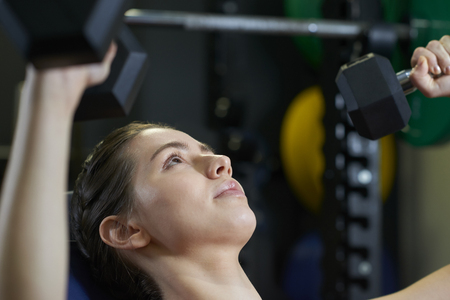 Woman In Gym Exercising With Weightsの写真素材