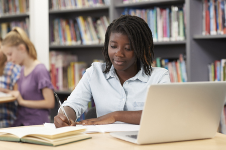 Female High School Student Working At Laptop In Libraryの写真素材