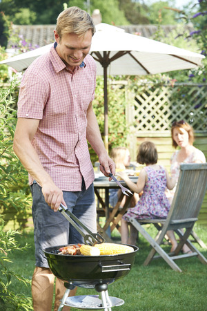 Father Cooking Barbeque For Family In Garden At Homeの写真素材