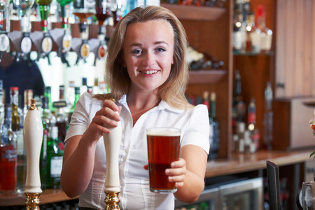 Female Bartender Serving Beer Behind Counter