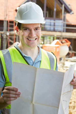 Portrait Of Construction Worker On Building Site Looking At House Plansの写真素材