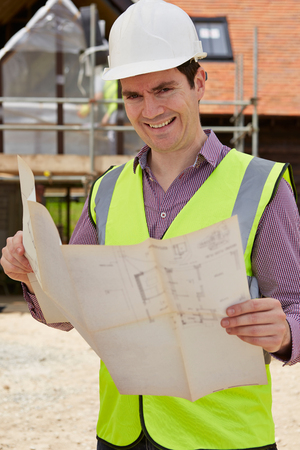 Portrait Of Architect On Building Site Looking At House Plansの写真素材