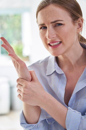 Portrait Of Woman In Pain Holding Wrist Suffering With Repetitive Strain Injuryの写真素材