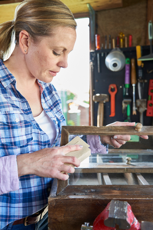 Mature Woman Upcycling Furniture In Workshop At Homeの写真素材