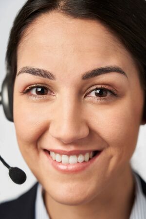 Portrait Of Smiling Businesswoman Wearing Telephone Headset In Customer Services Departmentの写真素材