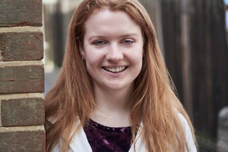 Portrait Of Smiling Teenage Girl Leaning Against Wall In Urban Settingの写真素材