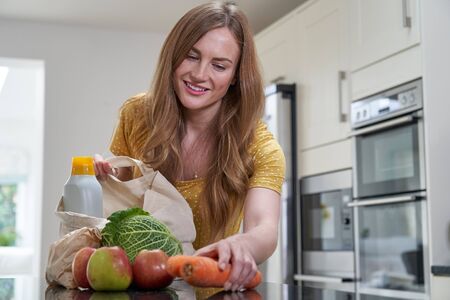 Woman Returning Home From Shopping Trip Unpacking Plastic Free Grocery Bagsの写真素材