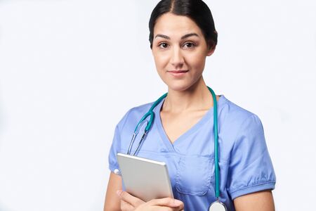 Studio Portrait Of Female Nurse Wearing Scrubs Holding Digital Tabletの写真素材