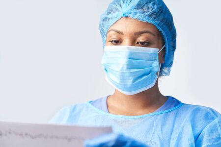 Studio Shot Of Female Surgeon Wearing Gown And Mask Holding Medical Print Outの写真素材