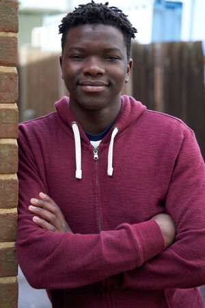 Portrait Of Smiling Teenage Boy Leaning Against Wall In Urban Settingの写真素材