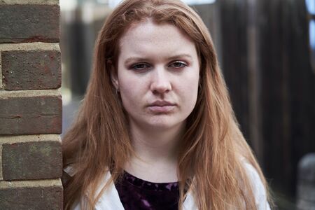 Portrait Of Serious Teenage Girl Leaning Against Wall In Urban Settingの写真素材