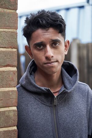 Portrait Of Teenage Boy Leaning Against Wall In Urban Settingの写真素材