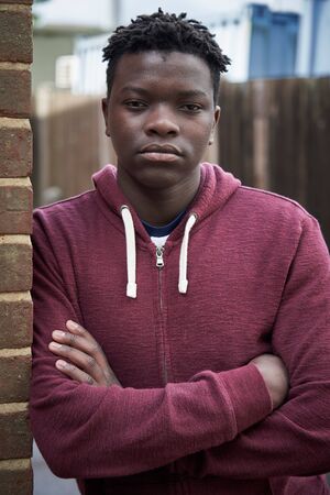 Portrait Of Teenage Boy Leaning Against Wall In Urban Settingの写真素材