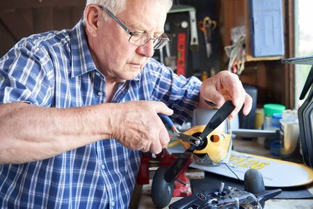 Senior Man Working On Model Radio Controlled Aeroplane In Shed At Homeの写真素材
