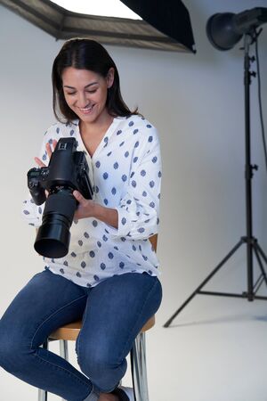 Female Photographer In Studio For Photo Shoot With Camera And Lighting Equipmentの写真素材