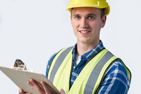 Studio Portrait Of Builder Architect With Clipboard Against White Backgroundの写真素材