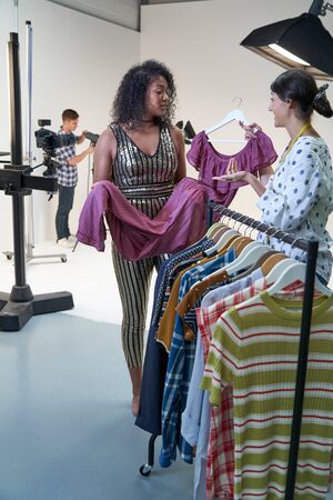 Stylist Choosing Clothes For Fashion To Wear On Photo Shoot In Studio