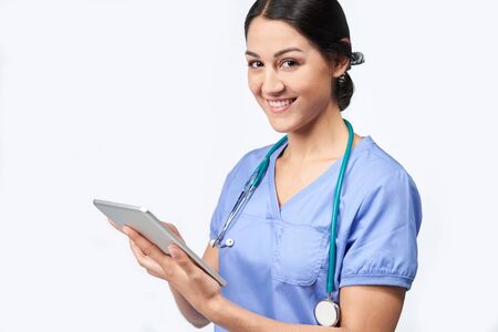 Portrait Of Studio Shot Of Female Nurse Wearing Scrubs Using Digital Tabletの写真素材