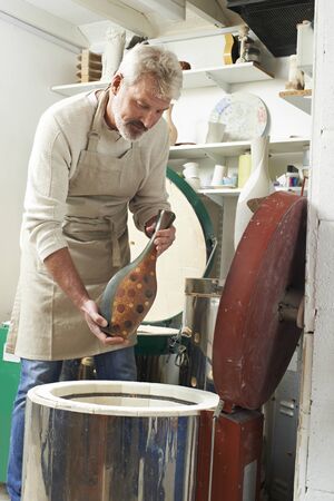 Mature  Man In Pottery Studio Firing Vase In Kilnの写真素材