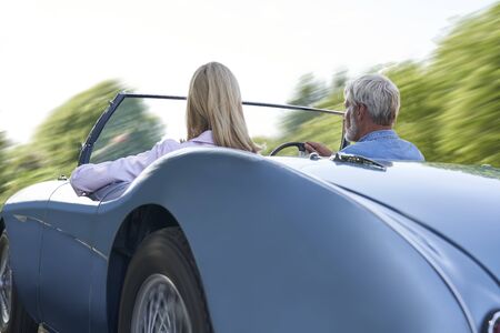 Rear View Of Mature Couple Enjoying Road Trip In Classic Open Top Sports Car Togetherの写真素材