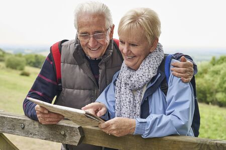 Retired Couple On Walking Holiday Resting On Gate With Mapの写真素材
