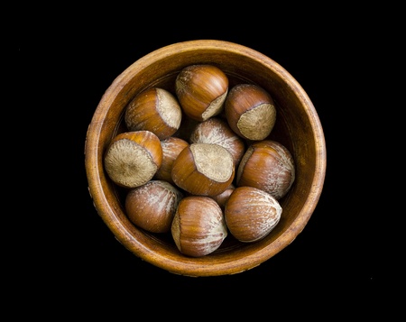 Bowl full of hazel nuts isolated on blackの写真素材