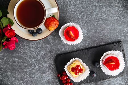 Top view on hot black tea in a cute cup with strawberry dessert, horizontalの写真素材