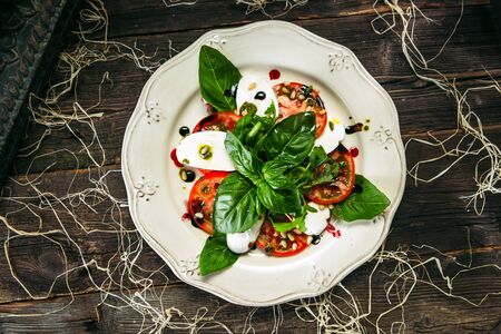 Top view on appetizing italian caprese salad tomatoes and mozzarella on the wooden table, horizontalの写真素材