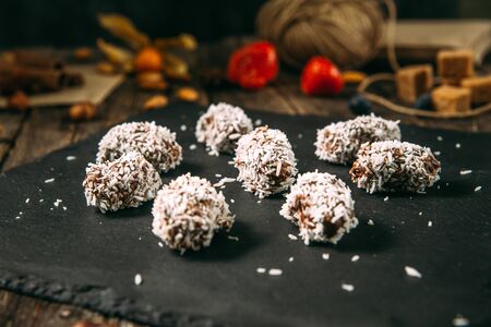 Side view on sweet appetizing chocolate sweets candies in coconut flakes on the balck background, horizontalの写真素材