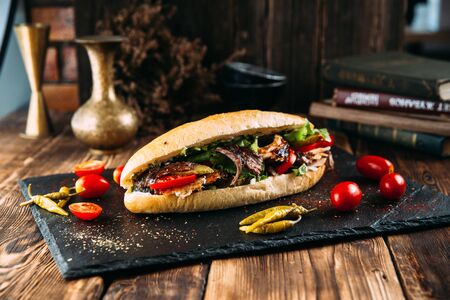 Appetizing juicy turkish doner in a loaf with marinated meat on the black board, horizontalの写真素材