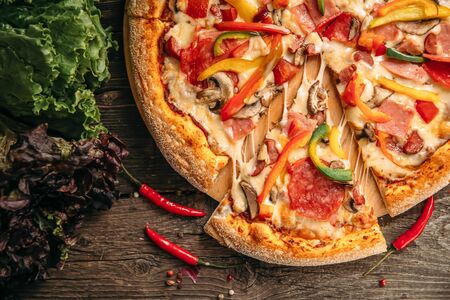 Top view closeup on appetizing italian capricciosa pizza on the wooden table, horizontalの写真素材