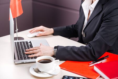 Working in office female hands with a laptop, calculator and a cup of coffee, horizontalの写真素材