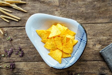 Top view on corn triangular chips on the wooden table, horizontal