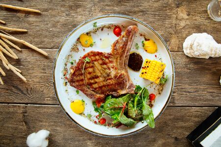 Top view on appetizing juicy pork chop with a corn on the wooden table, horizontalの写真素材