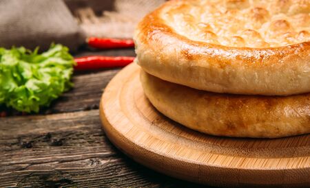 Closeup on uzbek flat cake lepeshka on a wooden board on the wooden table, horizontalの写真素材