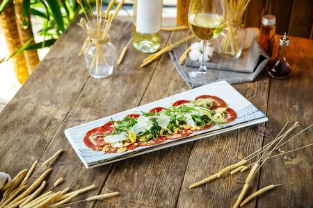 Side view on carpaccio meat with parmesan cheese and arugula on the wooden table, horizontalの写真素材