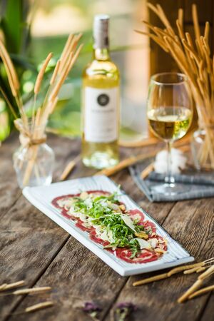 Side view on carpaccio meat with parmesan cheese and arugula on the wooden table, verticalの写真素材