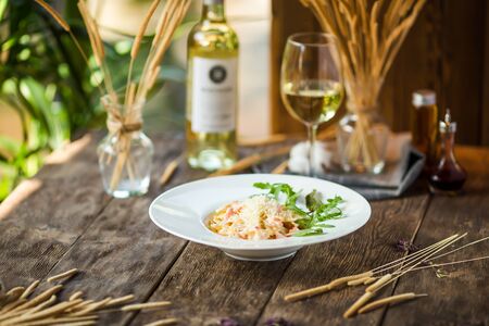 Italian pasta farfalle carbonara on the wooden table with white wine, horizontalの写真素材