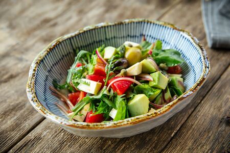 Closeup on healthy fresh salad with vegetables in a bowl on the wooden table, horizontalの写真素材