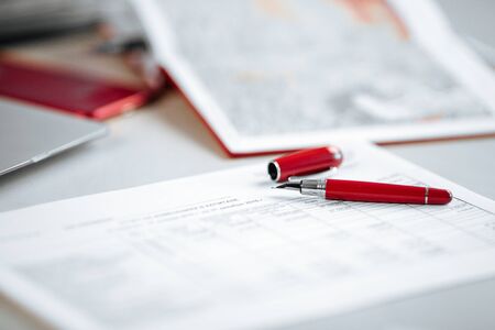 Closeup on a paper report red pen working place office, horizontalの写真素材