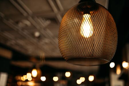 Interior with a beautiful mesh chandelier with a warm light bulb with a blurry background