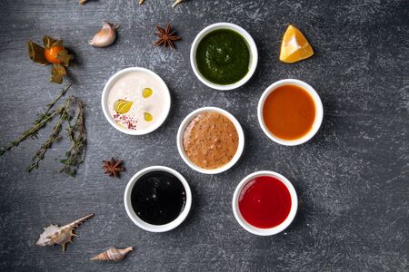 different types of sauces in gravy boats. Top view on a gray stucco background