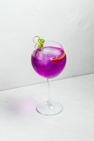 Unusual purple delicious alcoholic cocktail in a wine glass on the white background, verticalの写真素材