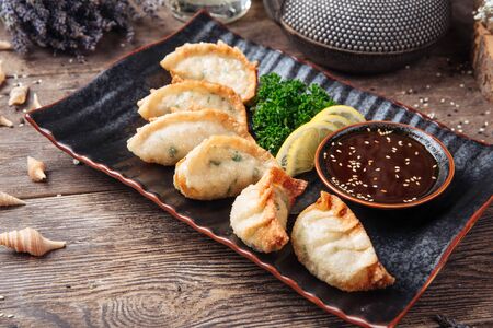 Closeup on fried japanese dumplings gedza with sauce on the wooden table, horizontalの写真素材
