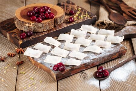 Side view on semi-finished cherry dumplings vareniki on the wooden board, horizontalの写真素材