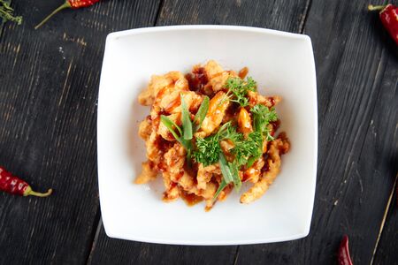 Top view on deep fried asian chicken in a white plate on the dark wooden table, horizontalの写真素材
