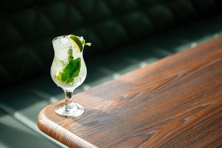 Refreshing cool mojito cocktail with ice lime and mint leaves in a glass on the corner of wooden table, horizontalの写真素材